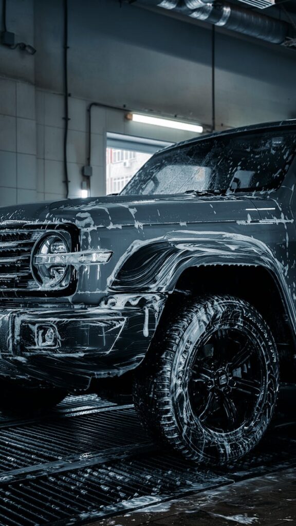 A sleek SUV with soap suds during a detailed car wash inside a garage.